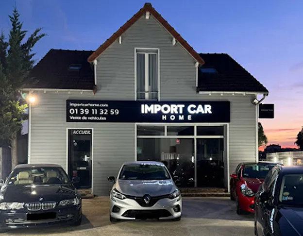 Façade de la concession Import Car Home avec des véhicules d'occasion garés devant au crépuscule à Poissy dans les Yvelines 78