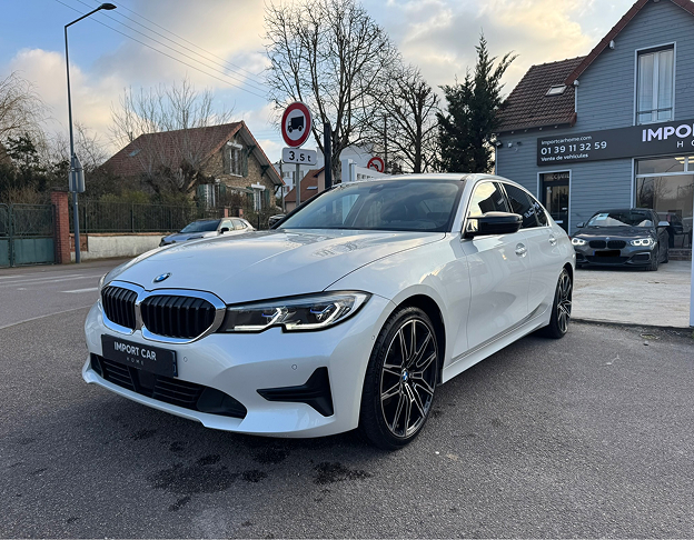 Berline BMW blanche stationnée devant un bâtiment de concession automobile Import Car Home à Poissy dans les Yvelines 78