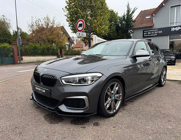 BMW Série 1 grise stationnée devant un garage automobile spécialisé en import de véhicules à Poissy dans les Yvelines 78
