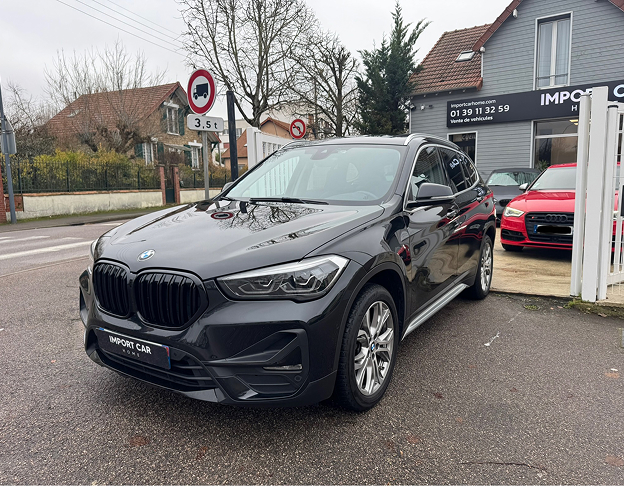 BMW X1 noir stationné devant une concession automobile avec une Audi rouge en arrière-plan à Poissy dans les Yvelines 78