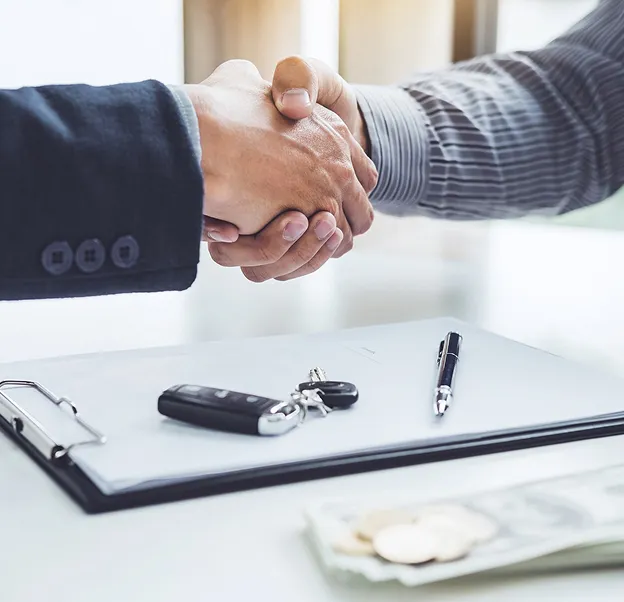 Poignée de main au-dessus d'un contrat avec clés de voiture et stylo sur le bureau à Poissy dans les Yvelines 78